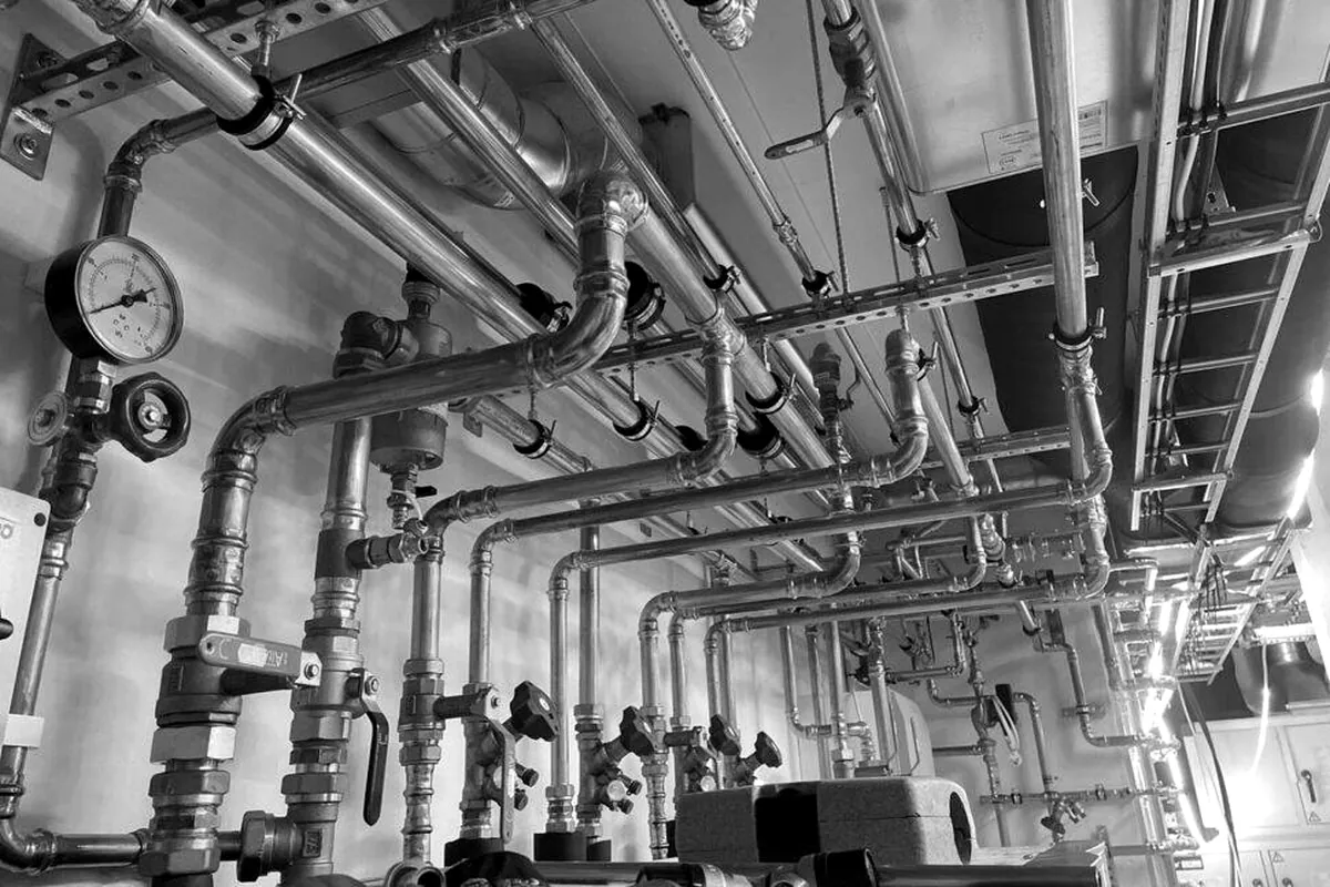Copper supply mains and valves running across a commercial mechanical room ceiling