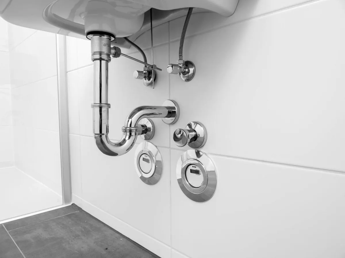 Finished chrome P-trap, supply stops, and trim under a wall-hung lavatory sink