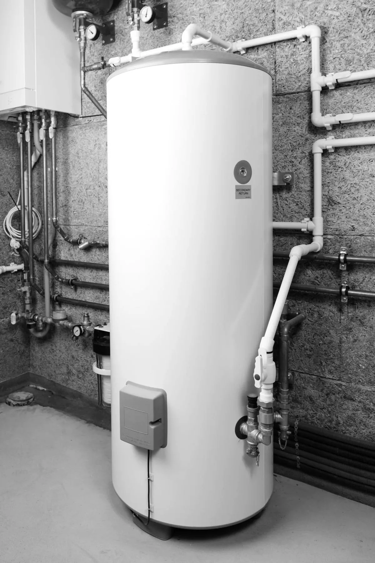 A tank water heater installed in a mechanical room with copper supply lines, shutoff valves, and an expansion tank